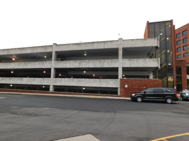 Three-story hospital parking garage with a car in the foreground.
