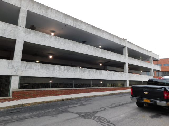 Three-story hospital parking garage with a car in the foreground.